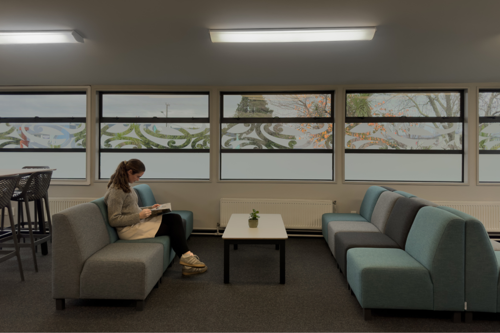 teacher-sitting-in-broadgreen-intermediate-staffroom-on-sofa-with-coffee-table-lsg-learning-spaces-global
